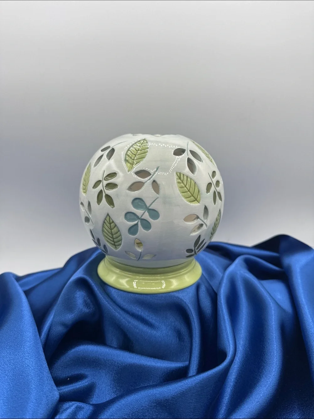 Ceramic illuminated globe/base featuring a pierced or cut-out floral design.